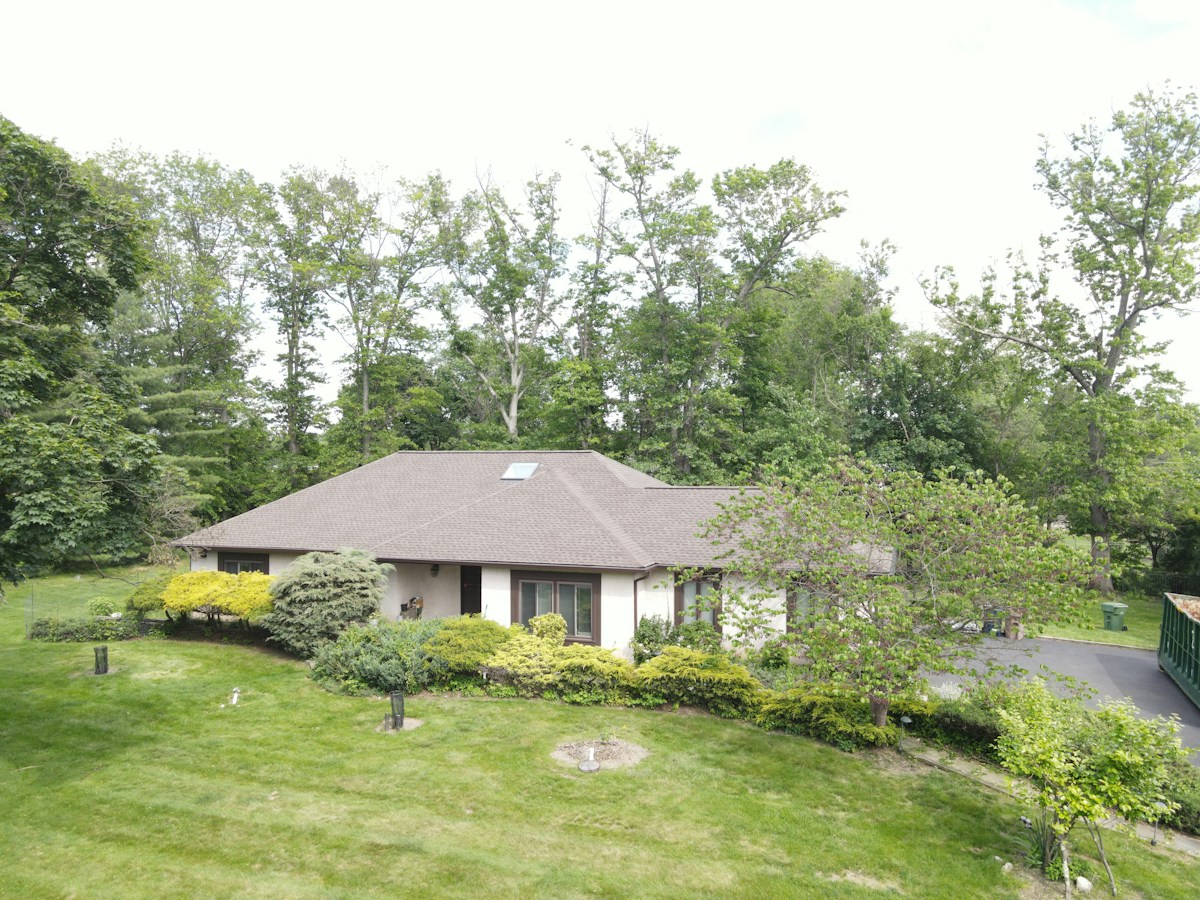 A house with intersecting shingle roof planes surrounded by trees