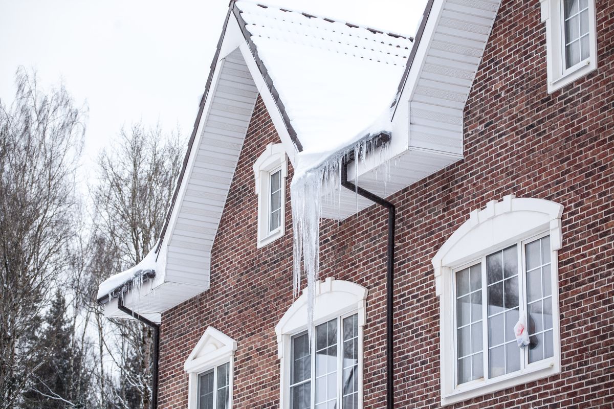 Snow and icicles along the eaves of a brick house