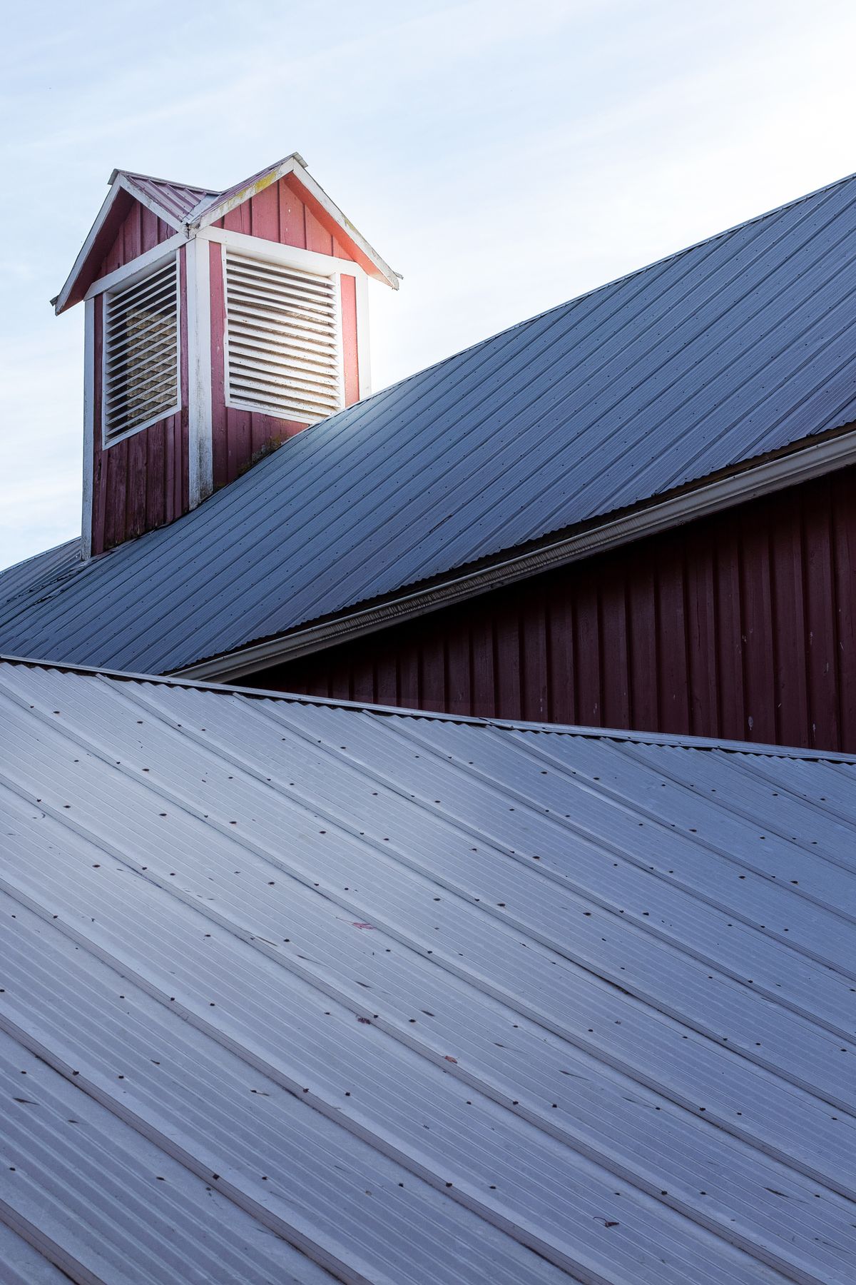 A metal roof with a raised ventilating cupola against the sky