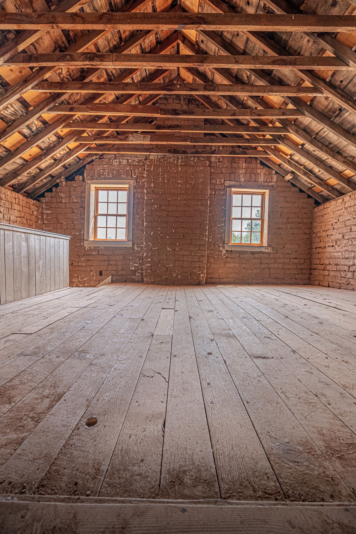 An unfinished attic with exposed roof framing and a board floor