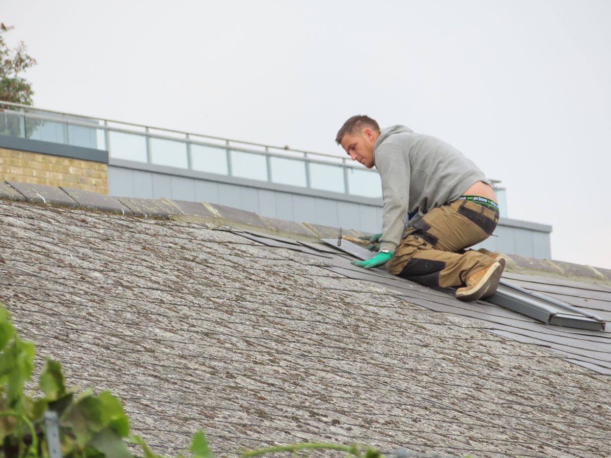 A roofer working over overlapping roof shingles