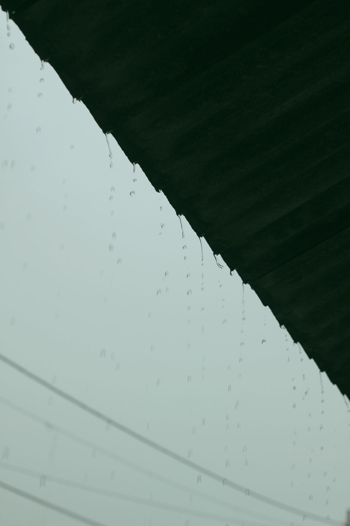 Rainwater dripping from a metal roof edge
